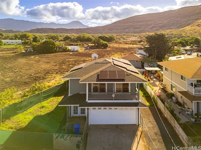 view of front of house with a garage, a fenced backyard, roof mounted solar panels, and a mountain view