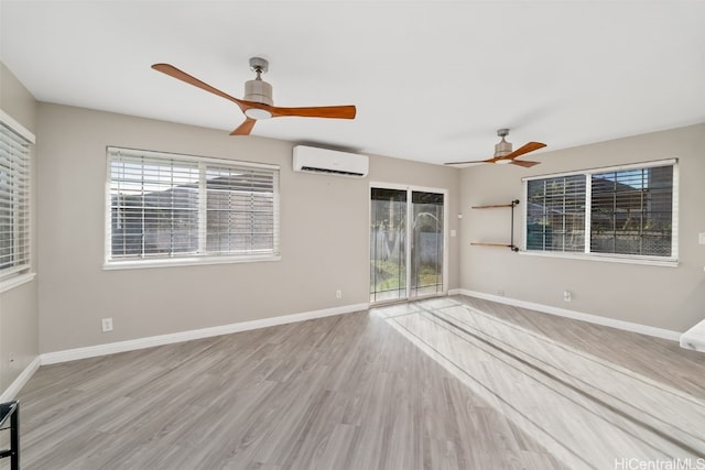 unfurnished room with a ceiling fan, light wood-style flooring, baseboards, and an AC wall unit