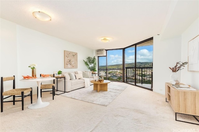 living room with expansive windows, light colored carpet, and a wall mounted AC