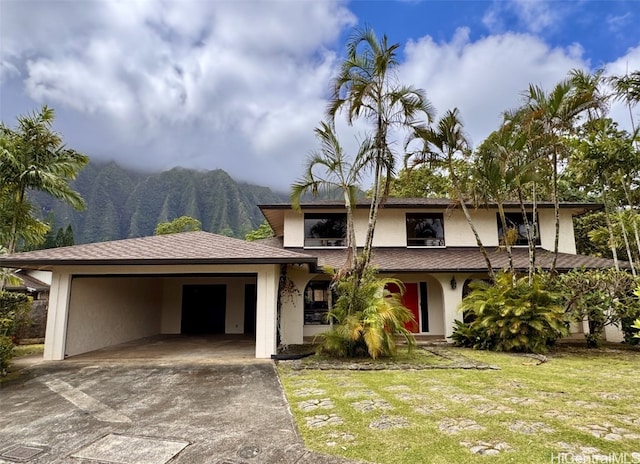 view of front facade featuring a carport, a mountain view, and a front lawn