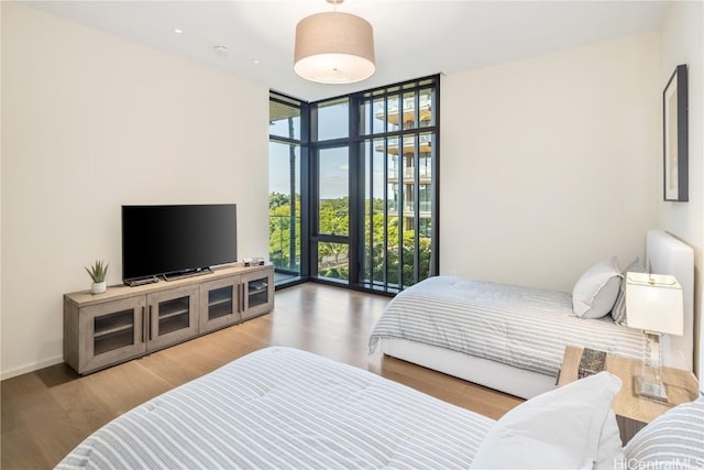 bedroom with a wall of windows and hardwood / wood-style flooring