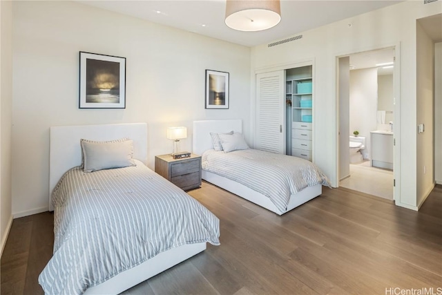 bedroom with ensuite bath, a closet, and hardwood / wood-style floors