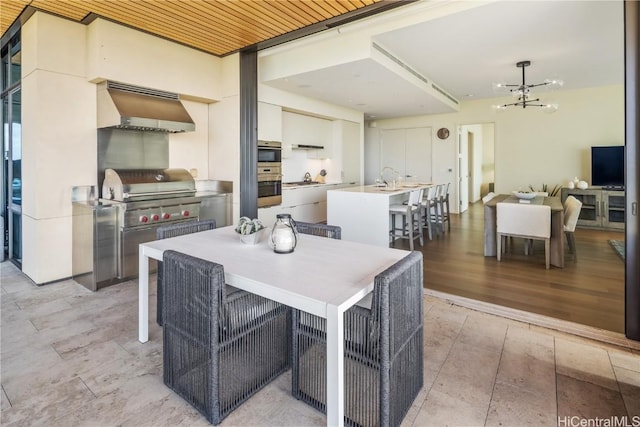 dining room featuring a notable chandelier, sink, light hardwood / wood-style floors, and wooden ceiling