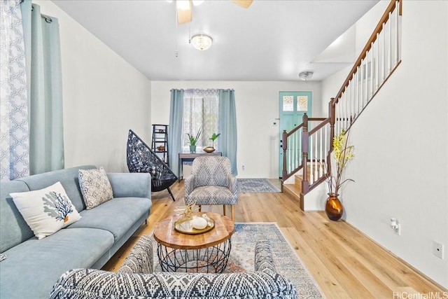 living room with a ceiling fan, wood finished floors, and stairs