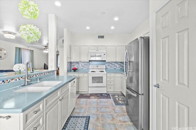 kitchen with a sink, visible vents, backsplash, a ceiling fan, and white appliances