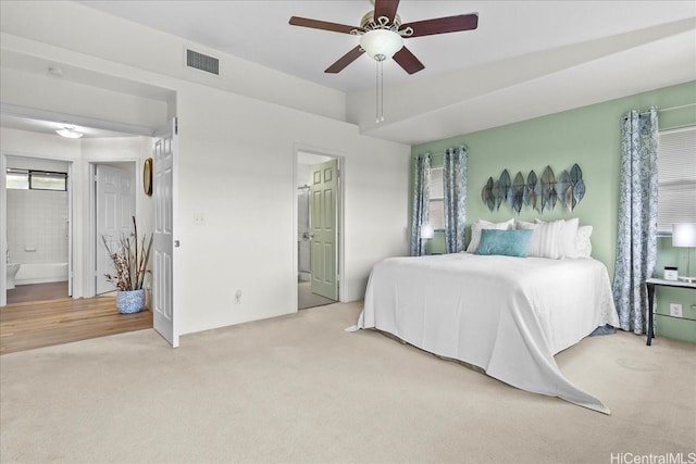 bedroom with ensuite bath, visible vents, light colored carpet, and multiple windows