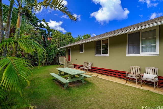 exterior space featuring a patio, a lawn, and stucco siding