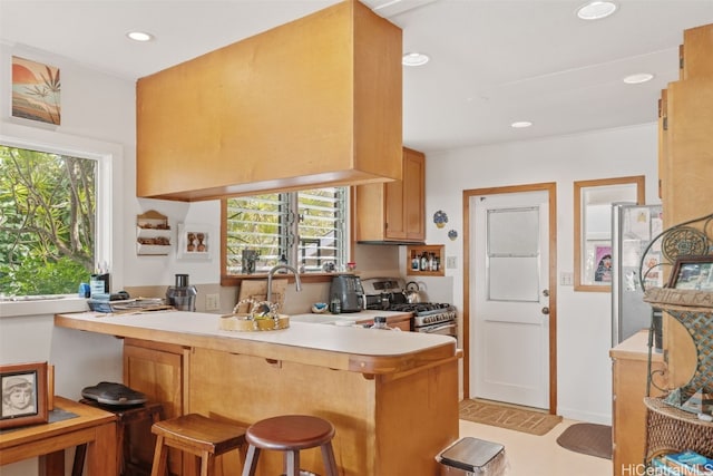 kitchen with a breakfast bar, a peninsula, stainless steel gas range, light countertops, and recessed lighting