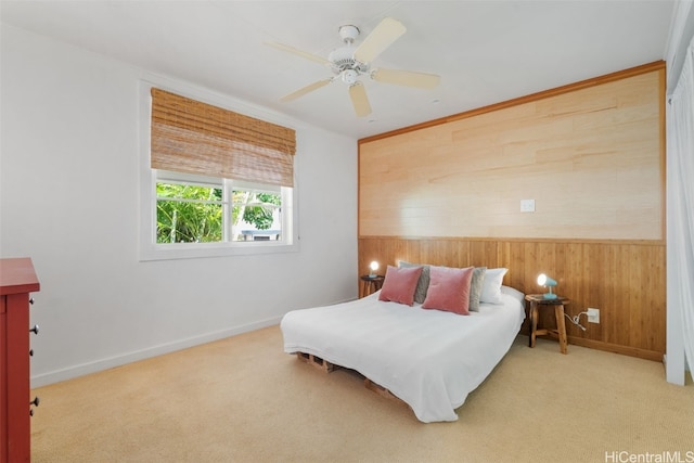 bedroom featuring carpet floors, wooden walls, baseboards, and a ceiling fan