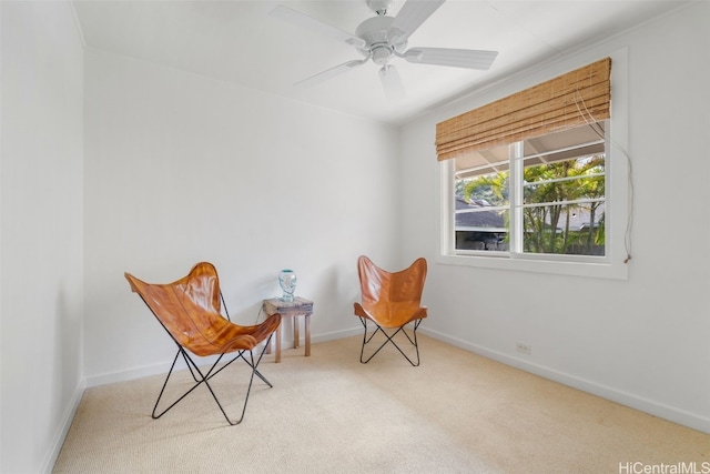 sitting room featuring carpet, baseboards, and a ceiling fan