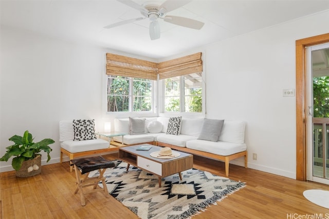 living area with a ceiling fan, light wood-style flooring, and baseboards