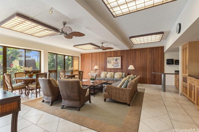 living room featuring a ceiling fan, wooden walls, and light tile patterned floors