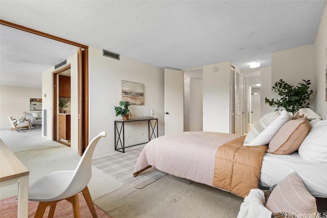 bedroom featuring a closet, visible vents, a textured ceiling, and light colored carpet