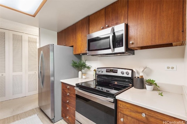 kitchen featuring appliances with stainless steel finishes, light countertops, and brown cabinetry