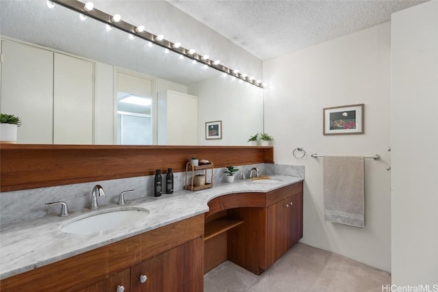 bathroom featuring double vanity, a textured ceiling, and a sink