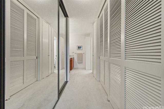 hall with a textured ceiling and light colored carpet