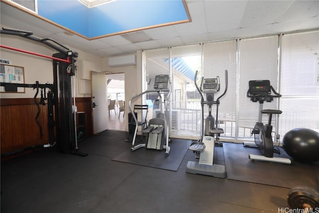 gym with wooden walls, visible vents, wainscoting, a paneled ceiling, and a wall mounted AC