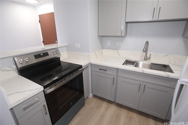 kitchen featuring gray cabinets, light wood-style floors, electric stove, and a sink