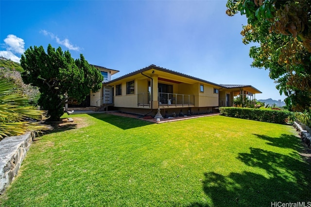 back of property with a lawn and stucco siding