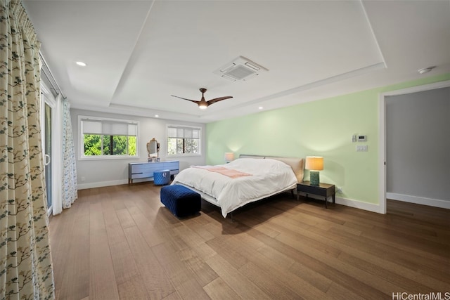 bedroom with wood finished floors, baseboards, recessed lighting, ceiling fan, and a raised ceiling