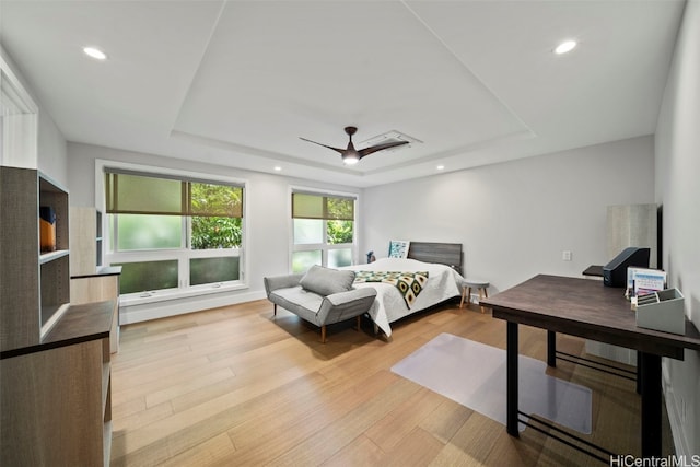 bedroom with a ceiling fan, a tray ceiling, recessed lighting, and wood finished floors