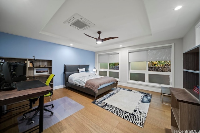 bedroom with a raised ceiling, a ceiling fan, wood finished floors, recessed lighting, and baseboards