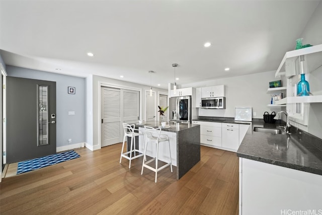 kitchen with open shelves, a sink, stainless steel appliances, white cabinets, and light wood-style floors