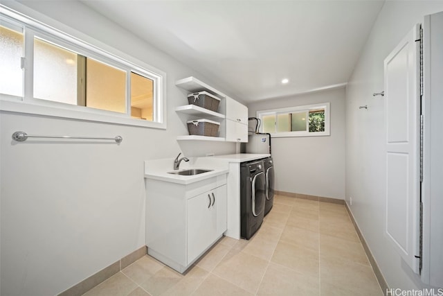 washroom featuring light tile patterned floors, baseboards, cabinet space, a sink, and washer and clothes dryer