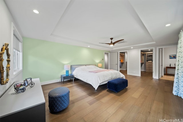 bedroom with baseboards, a tray ceiling, and wood finished floors