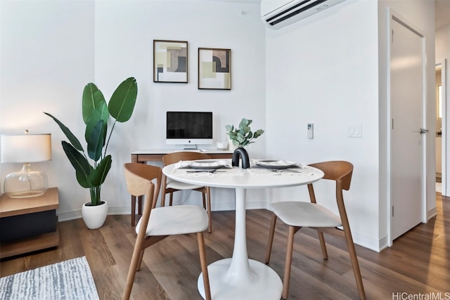 dining space featuring a wall mounted air conditioner, wood finished floors, and baseboards