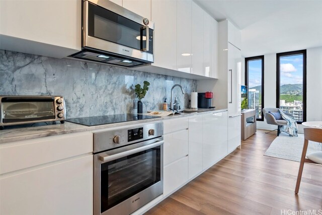 kitchen with tasteful backsplash, modern cabinets, appliances with stainless steel finishes, and white cabinets