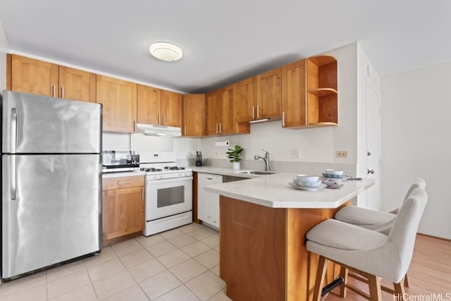 kitchen featuring open shelves, a peninsula, a sink, under cabinet range hood, and appliances with stainless steel finishes