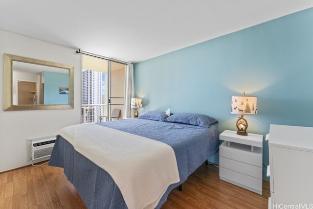 bedroom with wood finished floors and a wall mounted air conditioner