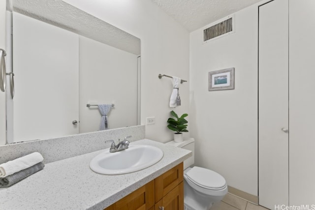 bathroom with vanity, visible vents, a textured ceiling, tile patterned floors, and toilet