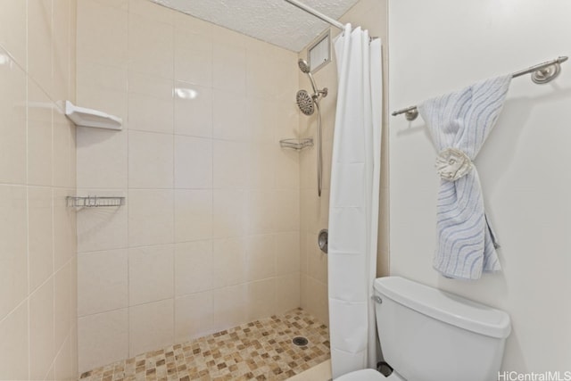 bathroom with a tile shower and toilet