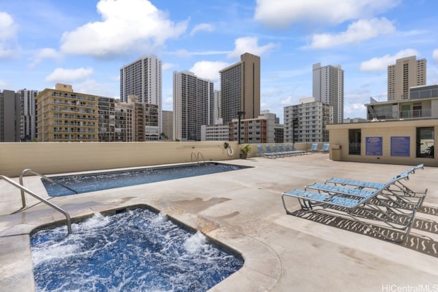 view of swimming pool with a view of city, a community hot tub, and a patio area