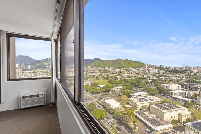 unfurnished sunroom featuring a city view, a mountain view, and a wall mounted AC