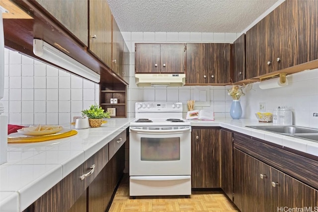 kitchen with under cabinet range hood, electric range, dark brown cabinets, and a textured ceiling