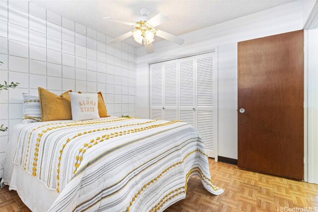 bedroom with a ceiling fan, a closet, and tile walls