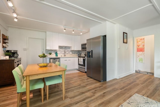 kitchen featuring white cabinetry, light countertops, appliances with stainless steel finishes, decorative backsplash, and light wood finished floors