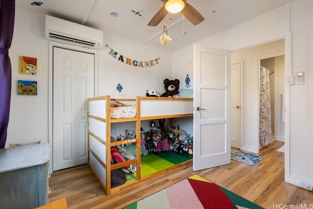 bedroom featuring wood finished floors, ceiling fan, and a wall mounted AC