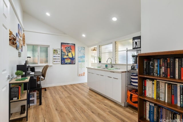 kitchen featuring white cabinets, light wood-type flooring, vaulted ceiling, and a wealth of natural light