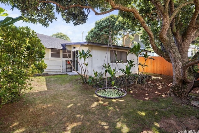 rear view of property featuring fence and a lawn