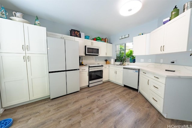 kitchen featuring appliances with stainless steel finishes, light wood-type flooring, and white cabinetry