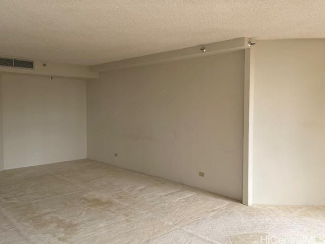 carpeted empty room featuring visible vents and a textured ceiling