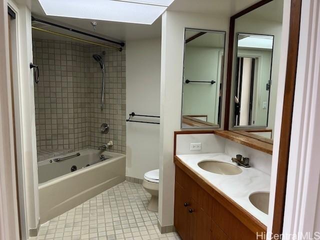 bathroom with double vanity, toilet, tub / shower combination, a sink, and baseboards