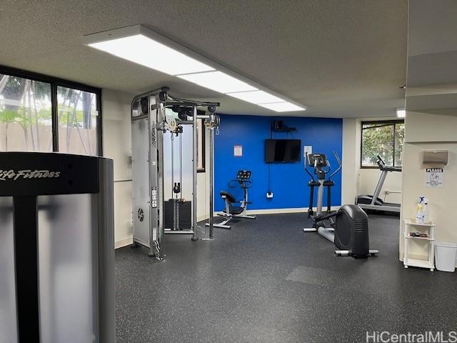 exercise room featuring a textured ceiling and baseboards