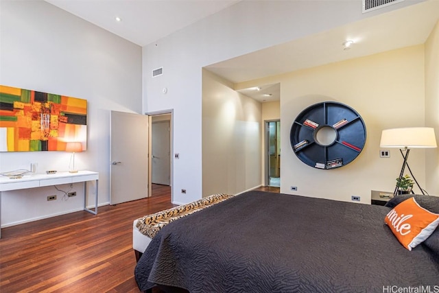 bedroom with visible vents, a towering ceiling, and wood finished floors