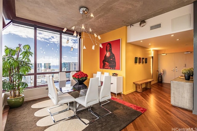 dining room featuring visible vents, a view of city, baseboards, and wood finished floors