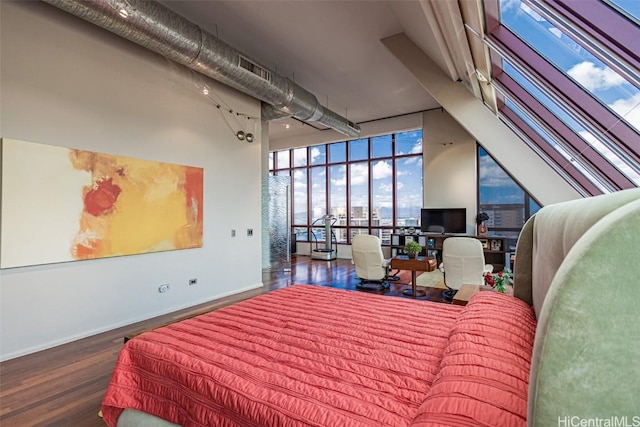 bedroom featuring floor to ceiling windows, a high ceiling, baseboards, and wood finished floors